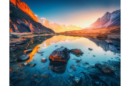 Mountains with illuminated peaks stones in mountain lake at sunset containing